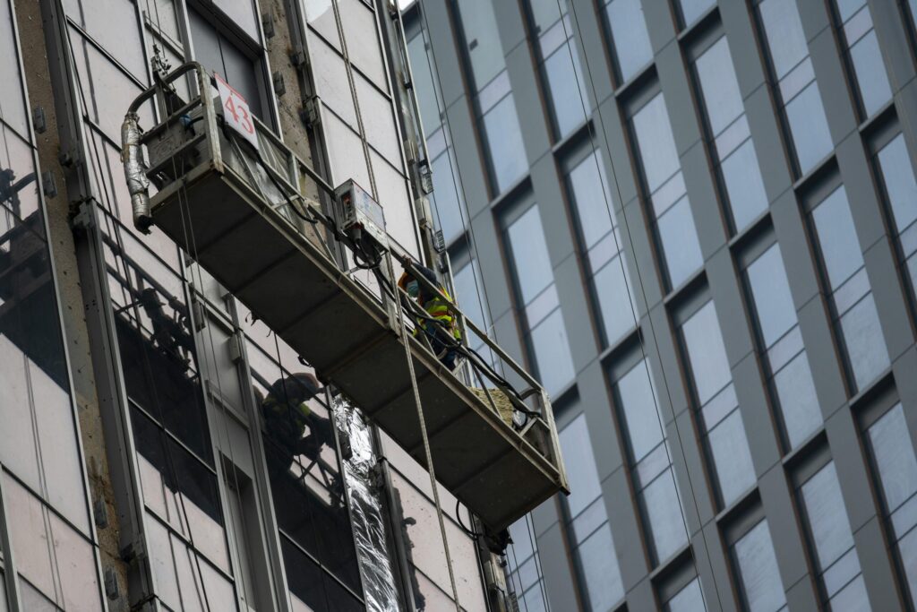 Worker on suspended scaffolding on high-rise building in Brooklyn, NY